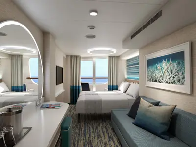 Moderne Balkonkabine der Carnival Jubilee mit Twin-Betten, Sofa, Schreibtisch und TV. Durch die Balkontür ist das Meer sichtbar. Maritime Dekoration in Blau- und Weißtönen.