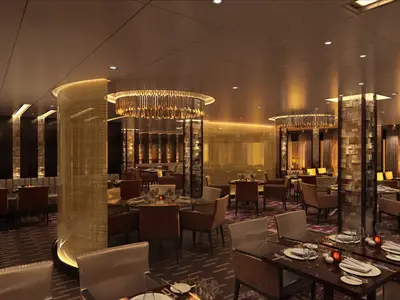 Innenansicht eines eleganten Restaurants auf der Carnival Jubilee. Mehrere Speisetische sind mit Geschirr und Gläsern gedeckt. Warme Goldtöne dominieren die Einrichtung mit runden Leuchtern und strukturierten Wänden.