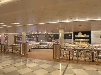 Innenansicht des modernen JavaBlue Cafes auf der Carnival Jubilee. Die Theke präsentiert Gebäck und Getraenke, umgeben von eleganten Sitzbereichen mit Tischen und Stühlen. Warme Beleuchtung betont die stilvolle Einrichtung.