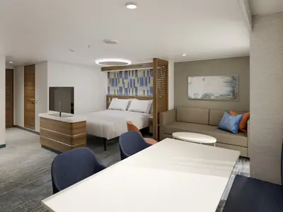 Geräumige, moderne Suite auf der Carnival Jubilee, unterteilt in Schlafbereich mit Doppelbett, Wohnbereich mit Sofa und Essbereich mit Tisch und Stühlen. Eine TV-Konsole trennt die Bereiche.