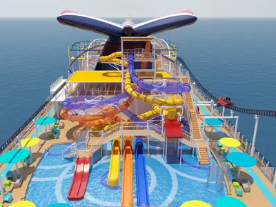 Vogelperspektive auf das obere Deck der Carnival Jubilee. Mehrere bunte Wasserrutschen, ein Poolbereich und eine rote Achterbahnfahrt sind zu sehen. Das Schiff fährt auf blauem Meer unter klarem Himmel.