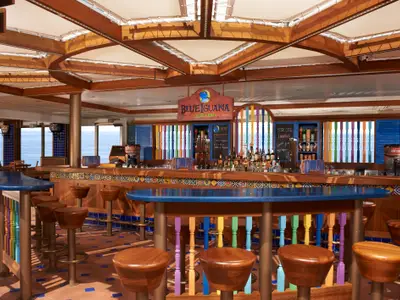 Die farbenfrohe "Blue Iguana Tequila Bar" an Bord der Carnival Liberty. Bunte Fliesen und Holzelemente prägen das Ambiente. Barhocker und eine Auswahl an Spirituosen sind zu sehen. Im Hintergrund das blaue Meer.