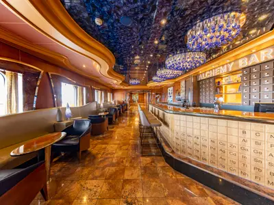 Moderne 'Alchemy Bar' auf der Carnival Luminosa. Barfront mit Periodensystem, blaue Kronleuchter und Sitzbereiche an den Fenstern.