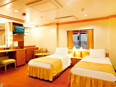 Helle Außenkabine auf der Carnival Miracle mit zwei Einzelbetten, Schreibtisch mit TV, und einem Fenster zur Reling. Warme Gelb- und Orangetöne dominieren den Raum.