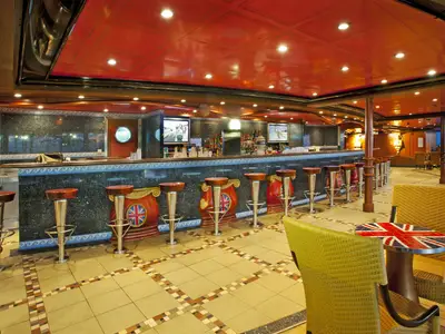 Innenansicht einer stilvollen Bar auf der Carnival Miracle mit einer langen Granit-Theke, Barhockern mit Union Jack-Design und gelben Korbstühlen.