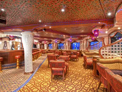 Opulente orientalische Bar und Lounge auf der Carnival Miracle. Reich gemusterte Decken, Teppich, Möbel in Rot-Gold. Bar mit Hockern, Sitzgruppen.