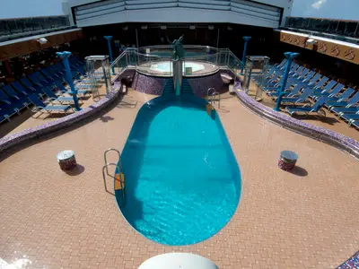 Blick von oben auf den Hauptpool der Carnival Miracle, umgeben von Liegestühlen. Im Hintergrund ein erhöhter Bereich mit Whirlpool und Statue.