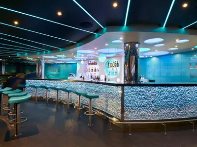 Moderne Liquid Lounge Bar. Geschwungene, blau beleuchtete Theke mit Barhockern. Spirituosenregale und blaue Wände. Futuristische Neonbeleuchtung.
