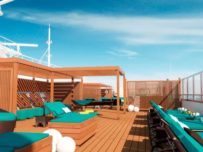 Ein sonniges Deck auf der modernen Carnival Radiance mit Holzboden, mehreren Liegestühlen mit türkisen Auflagen und Holzpergolen. Der blaue Himmel mit leichten Wolken ist sichtbar. Im Hintergrund sind Teile der Schiffsstruktur zu sehen.