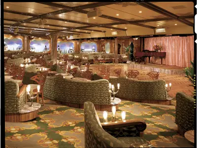 Weitläufige, elegante Schiffslounge mit grünen Sofas und Holzstühlen. Im Hintergrund: Winterlandschaftsbilder, Bühne mit Flügel. Warme Lichtinstallationen.