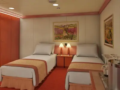 Eine Innenkabine auf der Carnival Splendor mit zwei Einzelbetten, Nachttischen, Lampen und einem Schrank. Roter Teppichboden und helle Wände mit Kunstwerken. Ein Eiskühler und Gläser stehen bereit.