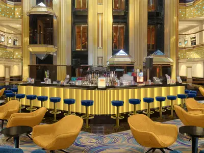 Luxuriöse Bar in einem Schiffsatrium mit goldener Einrichtung, blauen Hockern und gelben Sesseln. Mehrere Ebenen des Atriums sind sichtbar.