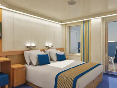 Innenansicht einer hellen Balkonkabine auf der Carnival Sunshine mit Doppelbett, Schreibtisch, Fernseher und Meerblick durch Balkontür und Fenster. Die Kabine ist in warmen Holztönen und blauen Akzenten gehalten.