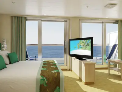 Geräumige Suite auf der Carnival Sunshine mit großem Bett, TV, Sofa und zwei Balkontüren mit Blick auf das offene Meer.