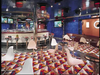 Innenansicht einer thematischen Bar mit langer Theke, Barhockern, Tischen und Stühlen. Blaue Wände und ein gemusterter Teppich.