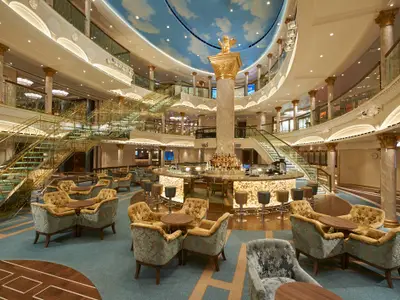 Opulentes Atrium der Carnival Venezia: zentrale Bar mit Lichtern, goldene Säulen, elegante Treppen mit Glasgeländern, gemusterte Polstersessel und ein blauer Wolkenhimmel an der Decke.
