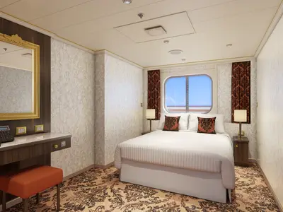 Geräumige Außenkabine auf der Carnival Venezia. Links ein Holzschreibtisch mit goldgerahmtem Spiegel. Rechts ein Doppelbett mit weißer Bettwäsche und braunen Kissen. Ein ovaler Ausblick auf das Meer ist durch das Fenster sichtbar.