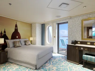 Blick in eine helle Balkonkabine der Carnival Venezia. Ein großes Doppelbett steht im Vordergrund, dahinter eine Wand mit einem Wandbild von Kuppeln. Rechts ein Schreibtisch mit Spiegel und ein Balkon mit Meerblick.