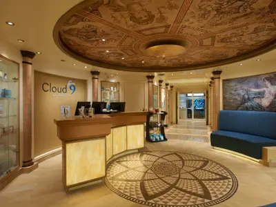 Der luxuriöse Empfangsbereich des Cloud 9 Spa mit einem geschwungenen Tresen. An der Decke prangt eine aufwendige Bemalung. Rechts befindet sich eine blaue Sitzbank unter einem Gemälde. Der Boden ist mit einem kunstvollen Mosaik verziert.