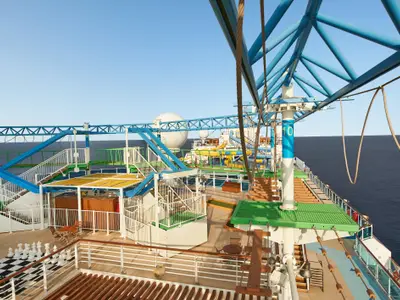 Vogelperspektive auf das Sport- und Aktivitätsdeck der Carnival Venezia. Zu sehen sind ein Hochseilgarten mit blauen Stahlträgern, ein Minigolfplatz, ein riesiges Schachbrett und im Hintergrund bunte Wasserrutschen. Rechts das weite Meer.
