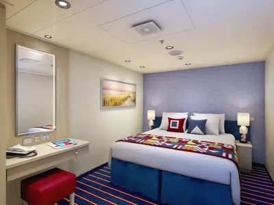 Geräumige Innenkabine der Carnival Vista mit einem Doppelbett und dekorativer Tagesdecke, einem Schminktisch mit Spiegel und Telefon auf der linken Seite. Die Wände sind hell, eine Akzentwand in Lavendelblau. Marine-Dekor.