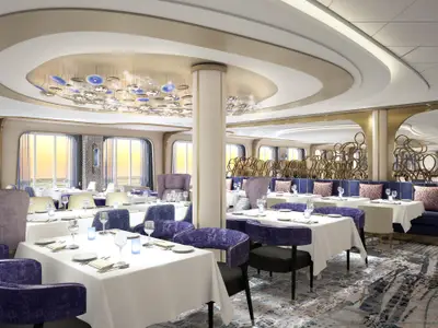 Modernes Restaurant an Bord der Celebrity Ascent. Zahlreiche gedeckte Tische mit violetten Stühlen und blauen Sitzbänken. Große Fenster mit Meerblick, eine auffällige Deckenleuchte und goldene Dekorationen bestimmen das stilvolle Ambiente.