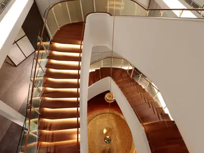 Luxuriöses Atrium mit geschwungenen Holztreppen, stimmungsvoller Beleuchtung und dekorativen Elementen.