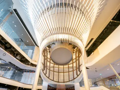 Modernes, mehrstöckiges Atrium mit beeindruckender Deckenbeleuchtung und Glasgeländern.