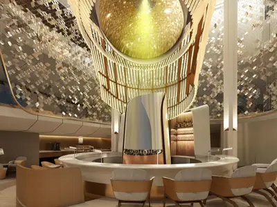 Luxuriöser Bar- und Loungebereich der Celebrity Edge mit zentraler, runder Bar und skulpturaler Säule. Eine glänzende Gold-Deckeninstallation mit Lichteffekten prägt das moderne Interieur.