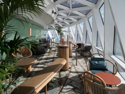 Sonnige Lounge auf der Celebrity Edge mit großen Fenstern zum Meer, vielen Pflanzen, modernen Möbeln und einem farbigen Teppich.