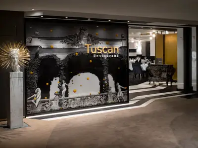 Stilvoller Eingangsbereich und Interieur des Tuscan Restaurants mit Kunstinstallation und goldener Schrift.