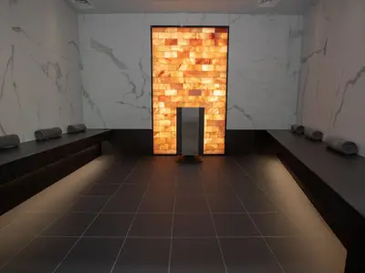 Modernes Spa mit leuchtender Salzwand, Sitzbänken und gerollten Handtüchern.
