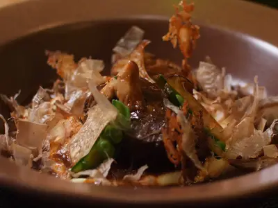 Nahaufnahme eines schön angerichteten Gerichts mit Katsuobushi und Gemüse in einer Schale.
