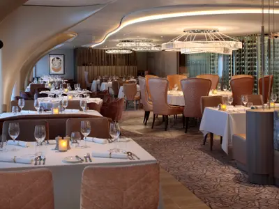 Elegantes Spezialitätenrestaurant mit stilvollem Ambiente, gedeckten Tischen und Weinregal.