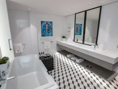 Ein helles, luxuriöses Badezimmer mit einer freistehenden Badewanne im Vordergrund, einem Doppelwaschtisch mit großem Spiegel und einer markanten schwarz-weiß gemusterten Fliesenboden.