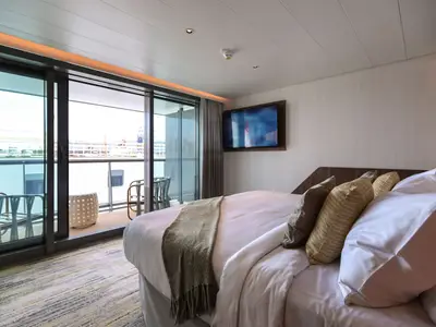 Helle Balkonkabine mit modernem Dekor, bequemes Bett und Ausblick auf den Hafen.