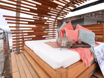 Gemütliche Cabana auf dem Sonnendeck mit Tagesbett und Blick auf das Wasser.