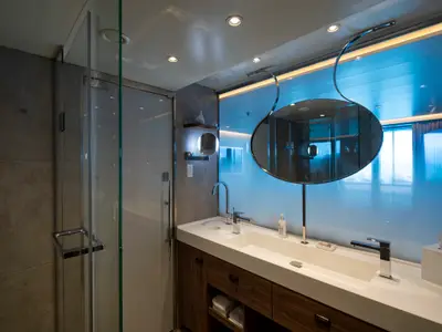 Modernes, luxuriöses Badezimmer einer Suite mit Doppelwaschbecken, Glasdusche und stilvollem Spiegel.