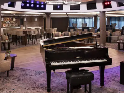 Die stilvolle Lounge der Celebrity Millennium zeigt einen schwarzen Yamaha-Flügel, eine gut ausgestattete Bar mit hohen Stühlen und mehrere gemütliche Sitzbereiche.