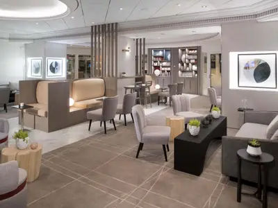 Helle Lounge der Celebrity Summit mit diversen Sitzgelegenheiten. Moderne Einrichtung, abstrakte Kunst, Pflanzen und eine Mischung aus Teppich- und Marmorboden.
