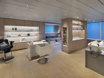 Ein stilvoller und modern eingerichteter Spa- und Salonbereich an Bord der Celebrity Summit. Zu sehen sind ein Frisierstuhl, ein Nagelstudio-Arbeitsplatz, eine Pediküre-Lounge und ein Haarwaschbecken.