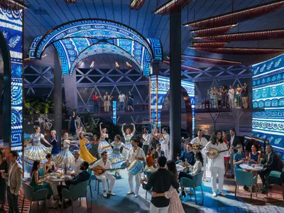 Blick in einen festlichen Raum der Celebrity Xcel mit tanzenden Personen, Live-Musik und Gästen. Blaue, gemusterte LED-Wände prägen das Design; im Hintergrund ist das Meer zu sehen.