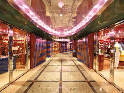 Blick durch die glänzende und farbenfrohe Shopping-Passage mit Boutiquen und spiegelnder Decke an Bord der Costa Deliziosa.