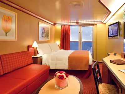 Blick in eine elegant eingerichtete Samsara Balkonkabine an Bord der Costa Deliziosa mit Doppelbett, rotem Sofa und Balkontür.