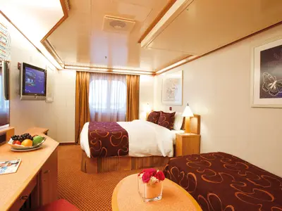 Eine gemütlich eingerichtete Außenkabine mit Fenster, Doppelbett und zusätzlichem Einzelbett an Bord der Costa Deliziosa.