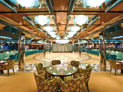 Großzügige Bar Mirabilis an Bord der Costa Deliziosa mit glänzenden Säulen, Tanzfläche, Bühne und stilvollen Sitzbereichen.