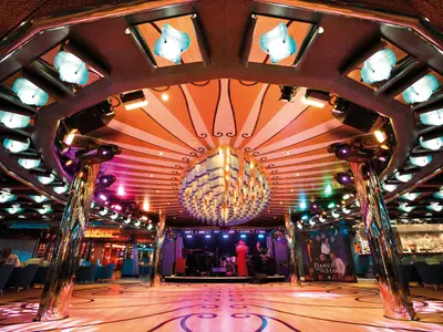 Bunt beleuchtete Grand Bar Mirabilis an Bord der Costa Deliziosa mit einer Tanzfläche, Bühne und einem auffälligen, spiralförmigen Deckendesign.