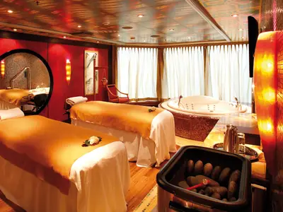 Ein gemütlicher Behandlungsraum im Samsara Spa an Bord der Costa Deliziosa mit zwei Massageliegen, einem Whirlpool und warmem Licht.