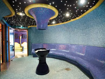 Der luxuriöse Samsara Spa an Bord der Costa Deliziosa mit blauen Mosaikfliesen an Wänden und Sitzbank. Die dunkle Decke gleicht einem Sternenhimmel.