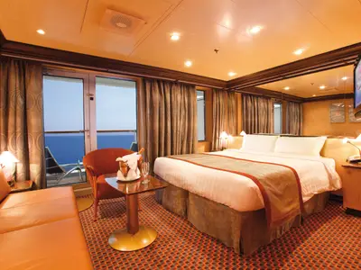Eine luxuriöse Suite an Bord der Costa Deliziosa mit großem Bett, bequemer Sitzecke, Meerblick-Balkon und Champagner. Das Zimmer ist elegant eingerichtet.